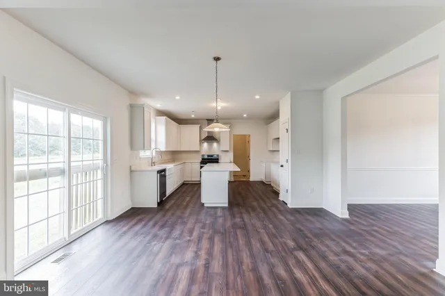 a large kitchen with white cabinets and wooden floor