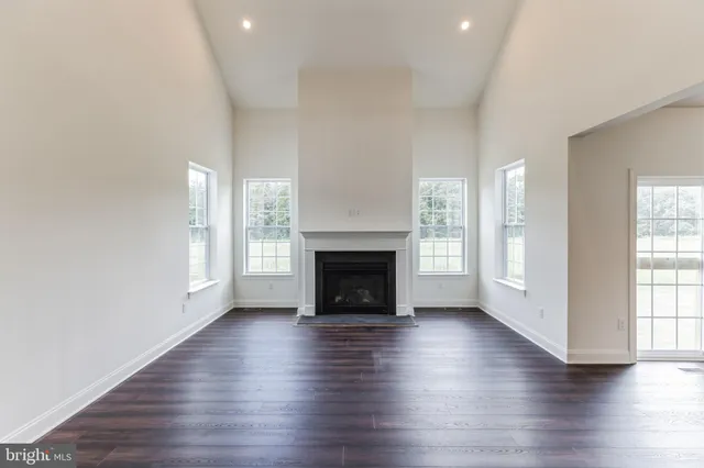 an empty room with wooden floor fireplace and windows