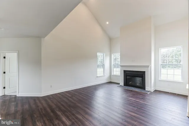 a view of an empty room with wooden floor fireplace and a window