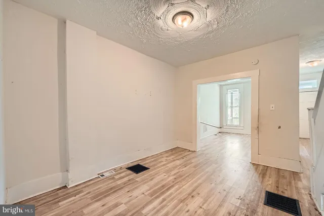 an empty room with wooden floor and window
