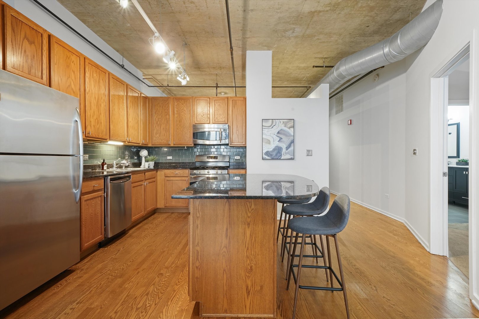 520 South State Street, Unit 503 Chicago, IL 60605 - Photo 7 of 25 a kitchen with granite countertop wooden floors refrigerator and cabinets
