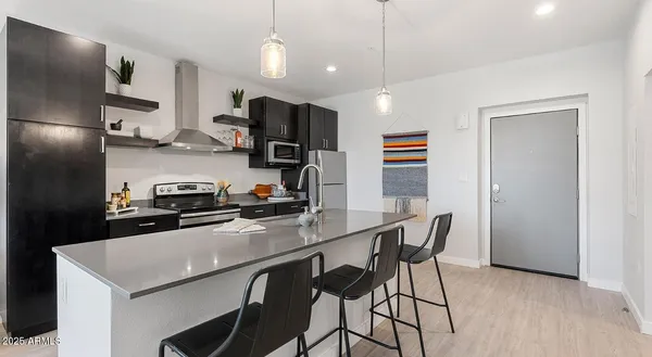 a kitchen with stainless steel appliances a table chairs refrigerator and microwave