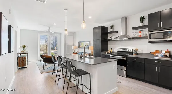 a kitchen with stainless steel appliances granite countertop a sink a stove a refrigerator and chairs