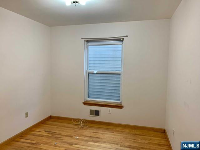 422 A Warren Street, Unit 1F Harrison, NJ 07029 - Photo 4 of 11 a view of an empty room with wooden floor and a window