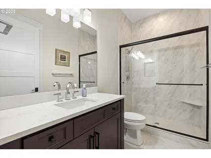 a bathroom with a sink a toilet a mirror and shower