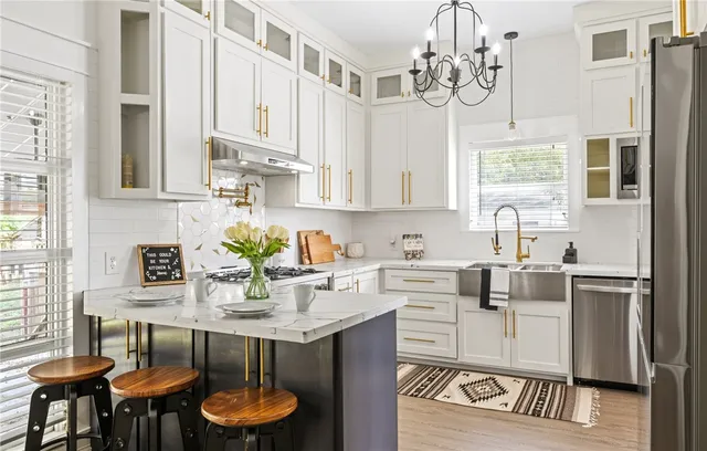 a kitchen with stainless steel appliances granite countertop a white refrigerator a sink dishwasher a dining table and chairs with wooden floor