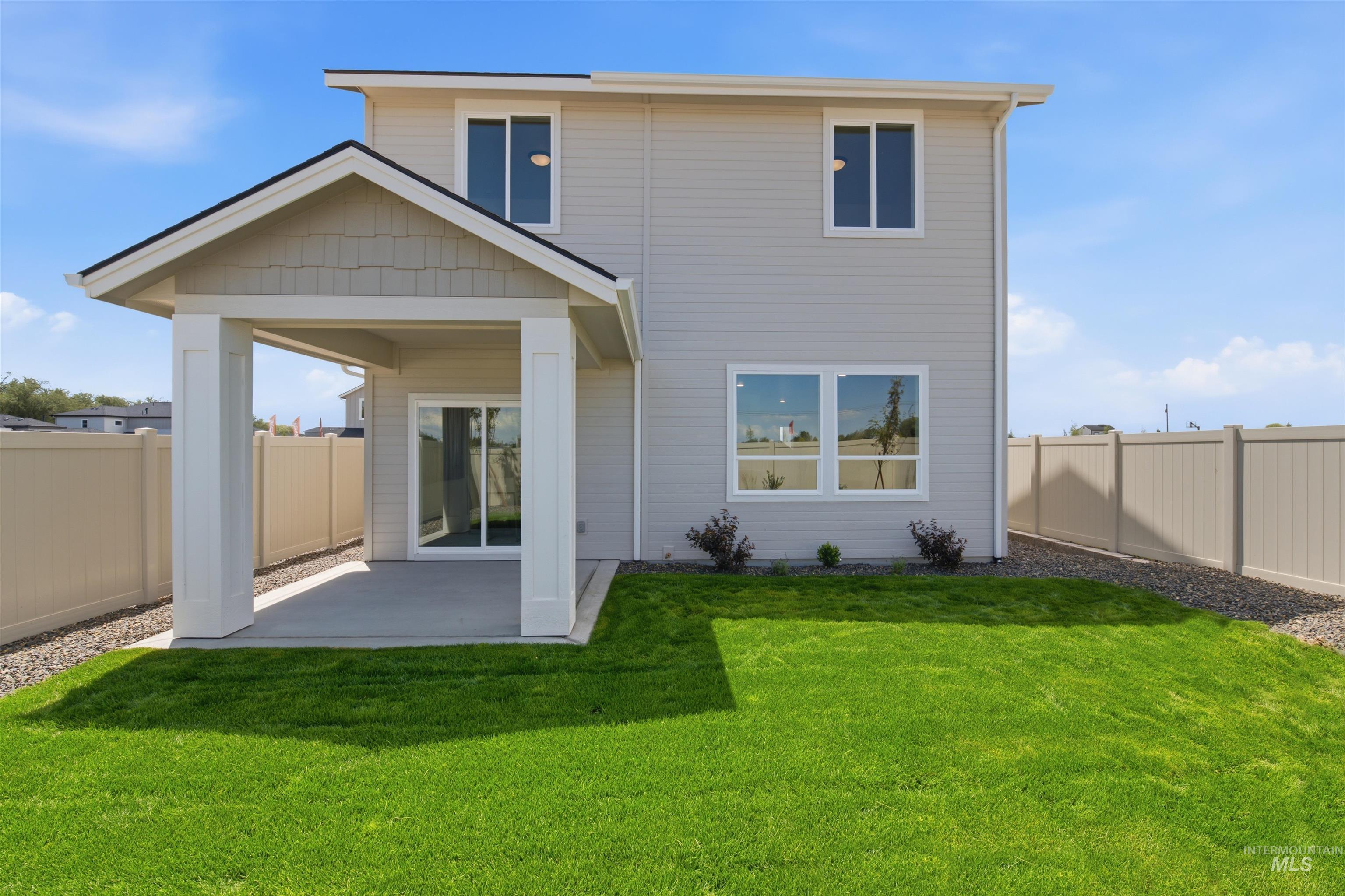 3405 Elliptical Lane Caldwell, ID 83607 - Photo 13 of 17 Rear exterior featuring a covered patio with a concrete slab, a sliding glass door, and a fenced yard with green lawn