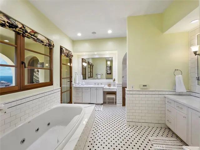 a bathroom with a tub a sink and a large mirror