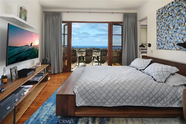 a bedroom with a large bed and a flat tv screen on dresser
