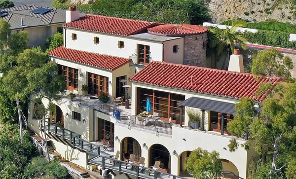 a view of a white house with large windows and a table and chairs