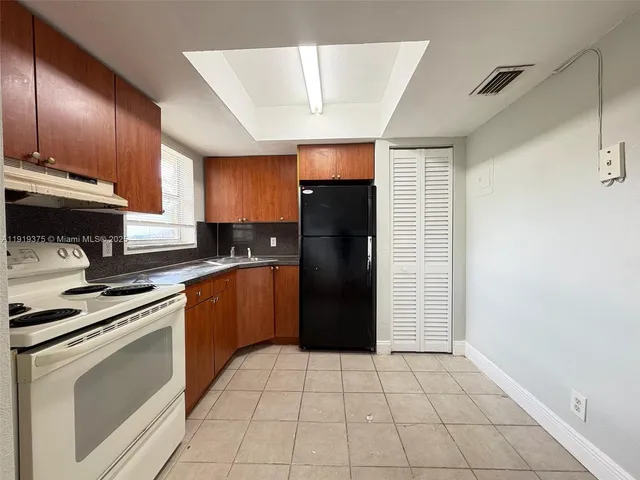 a kitchen with a refrigerator sink and cabinets