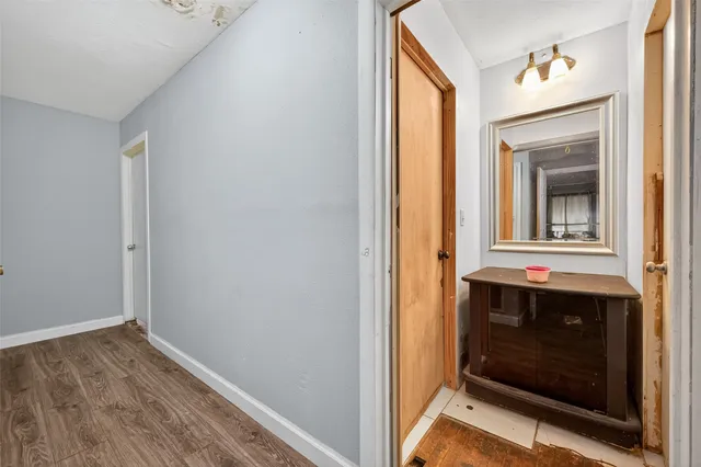 a view of a hallway with wooden floor and a bathroom