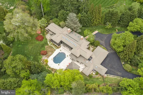 an aerial view of residential house with outdoor space and trees all around