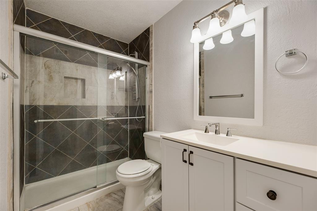 5109 Cedar Springs Road, Unit 105 Dallas, TX 75235 - Photo 10 of 16 Bathroom featuring a white vanity with an integrated sink, polished chrome faucet, and framed mirror