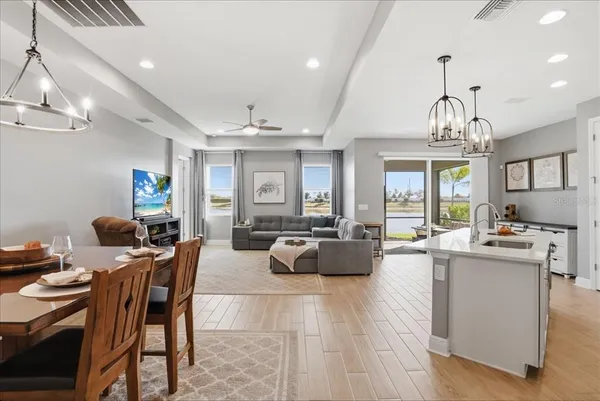 a living room with kitchen island furniture a chandelier and kitchen view