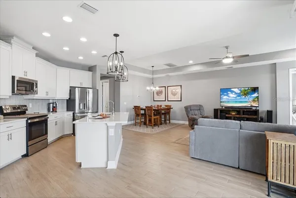 a kitchen with stainless steel appliances a refrigerator a sink dishwasher a stove and white cabinets with wooden floor