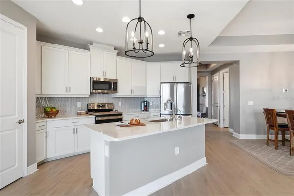 a kitchen with kitchen island granite countertop a stove a sink a dining table and chairs with wooden floor