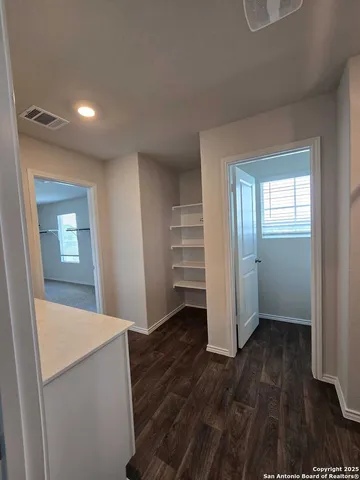 a view of hallway with wooden floor and cabinet
