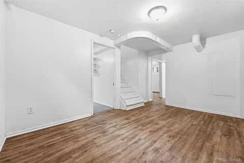 a view of an empty room with wooden floor and windows