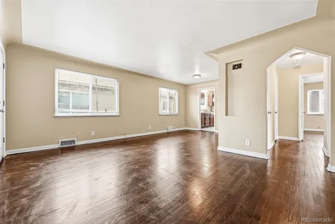 an empty room with wooden floor and windows