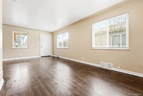 a view of an empty room with wooden floor and a window