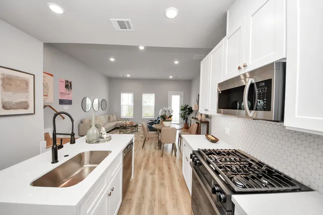 a kitchen with stainless steel appliances a sink a stove top oven a counter space and cabinets