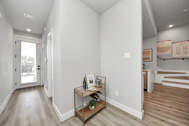 a view of a hallway to a livingroom with wooden floor and furniture