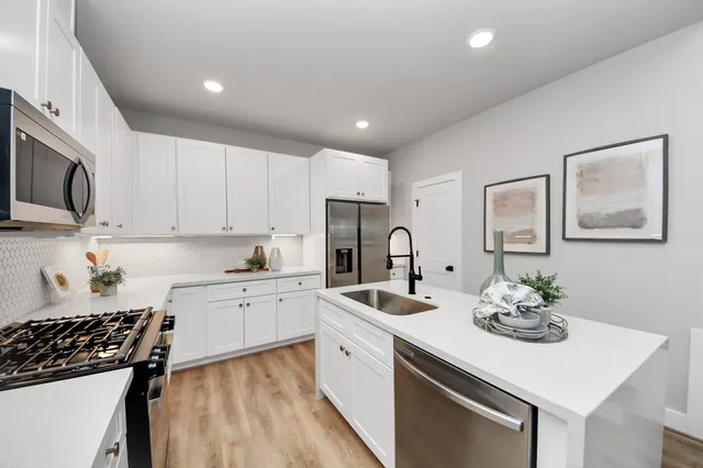 a kitchen with white cabinets and stainless steel appliances
