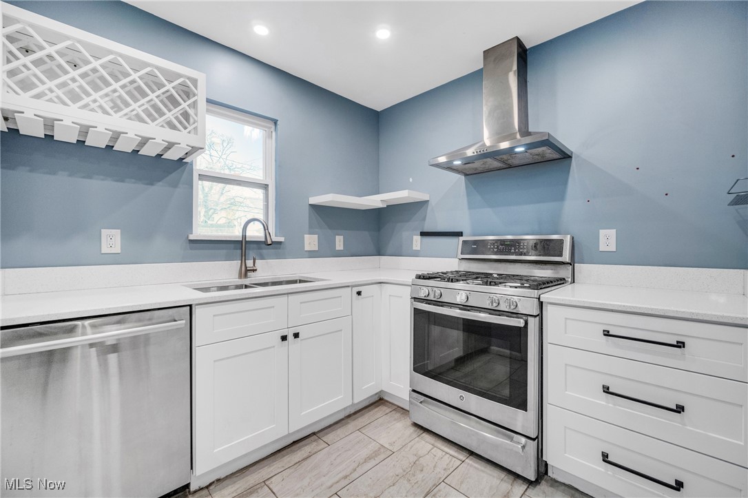 4430 Silsby Road Cleveland, OH 44118 - Photo 21 of 43 Kitchen with wall chimney exhaust hood, white cabinetry, sink, and appliances with stainless steel finishes