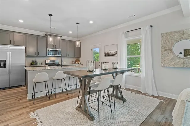 a kitchen with stainless steel appliances granite countertop a sink a stove a refrigerator cabinets and chairs