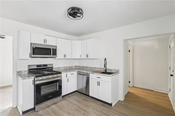 a kitchen with stainless steel appliances a stove a sink a microwave and cabinets