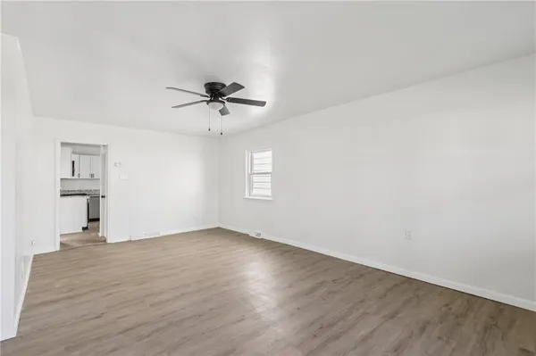 a view of an empty room with a window and wooden floor
