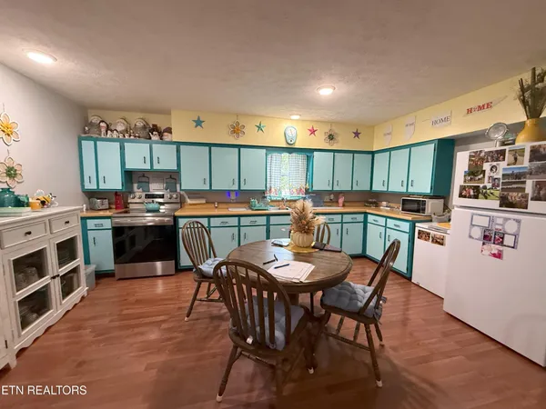 a kitchen with stainless steel appliances a stove a sink a oven a dining table and chairs