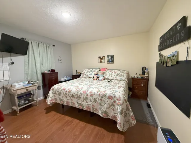 a bedroom with a bed and a flat tv screen on a dresser