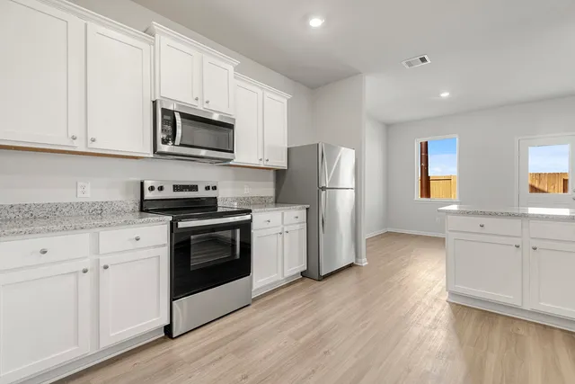 a view of an empty room with wooden floor and a ceiling fan