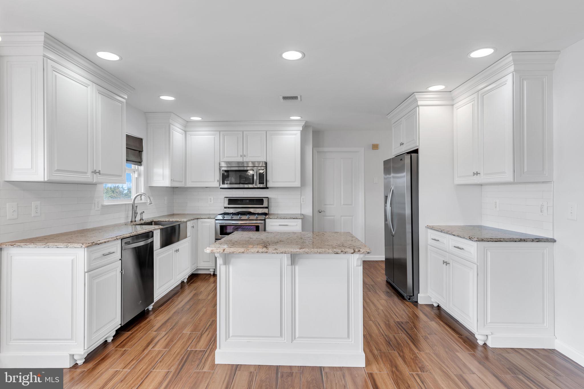 68 Morris Boulevard Manahawkin, NJ 08050 - Photo 11 of 43 a large kitchen with stainless steel appliances granite countertop a stove a sink a refrigerator and white cabinets with wooden floor