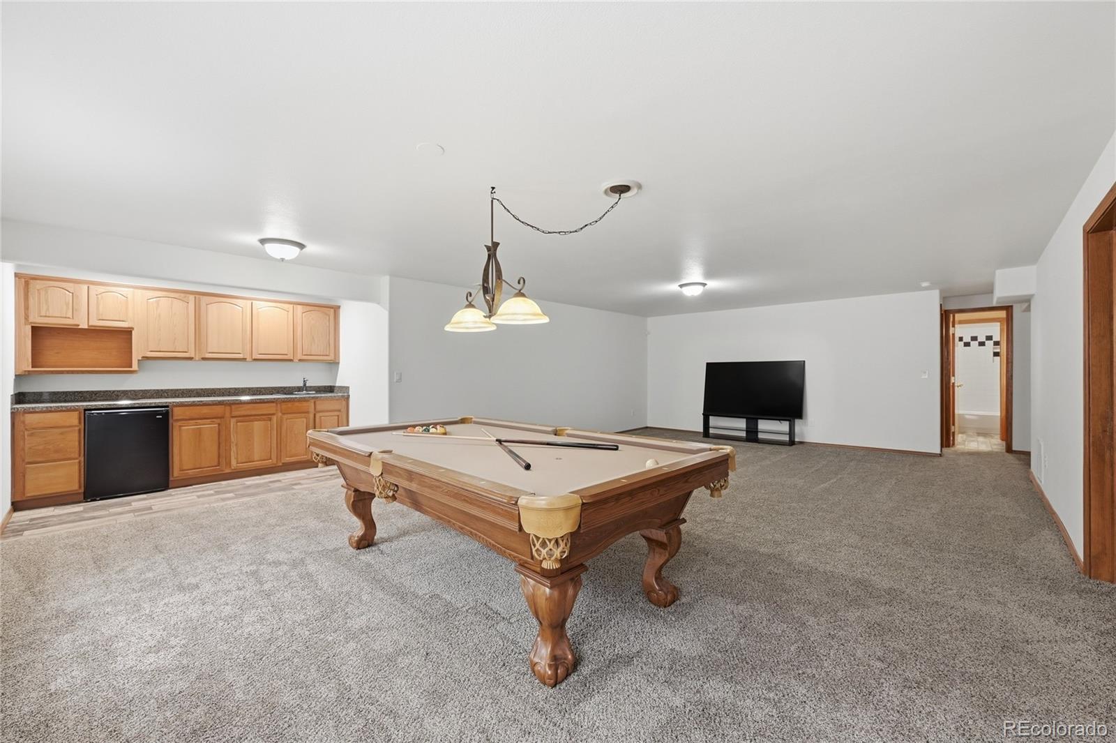 9288 Rockingham Drive Peyton, CO 80831 - Photo 27 of 49 a living room with game table and a flat screen tv
