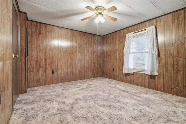 a view of a livingroom with a chandelier fan and windows