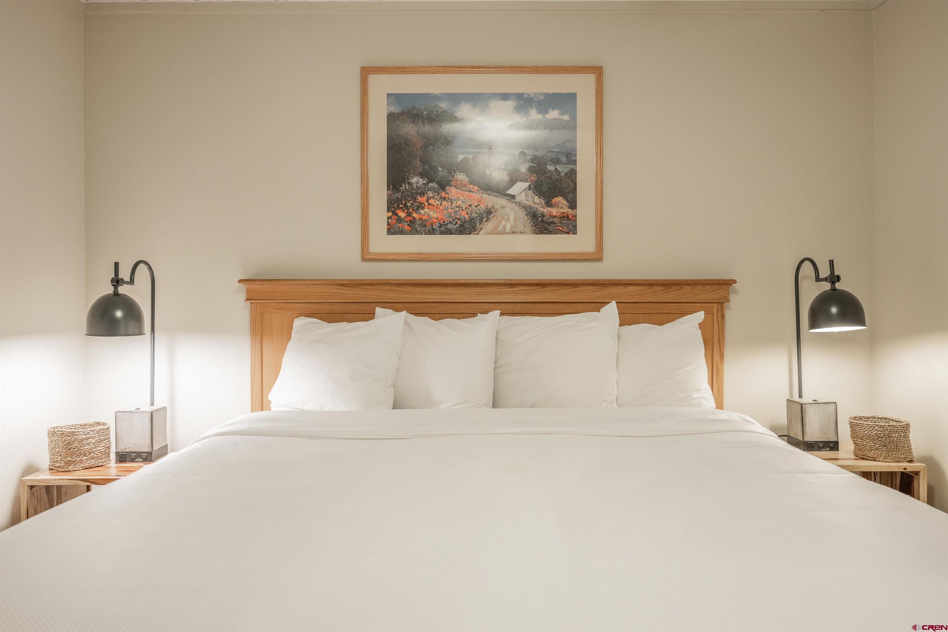 a bedroom with a bed and a painting on the wall