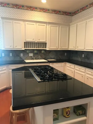 a kitchen with granite countertop a stove a sink and a microwave