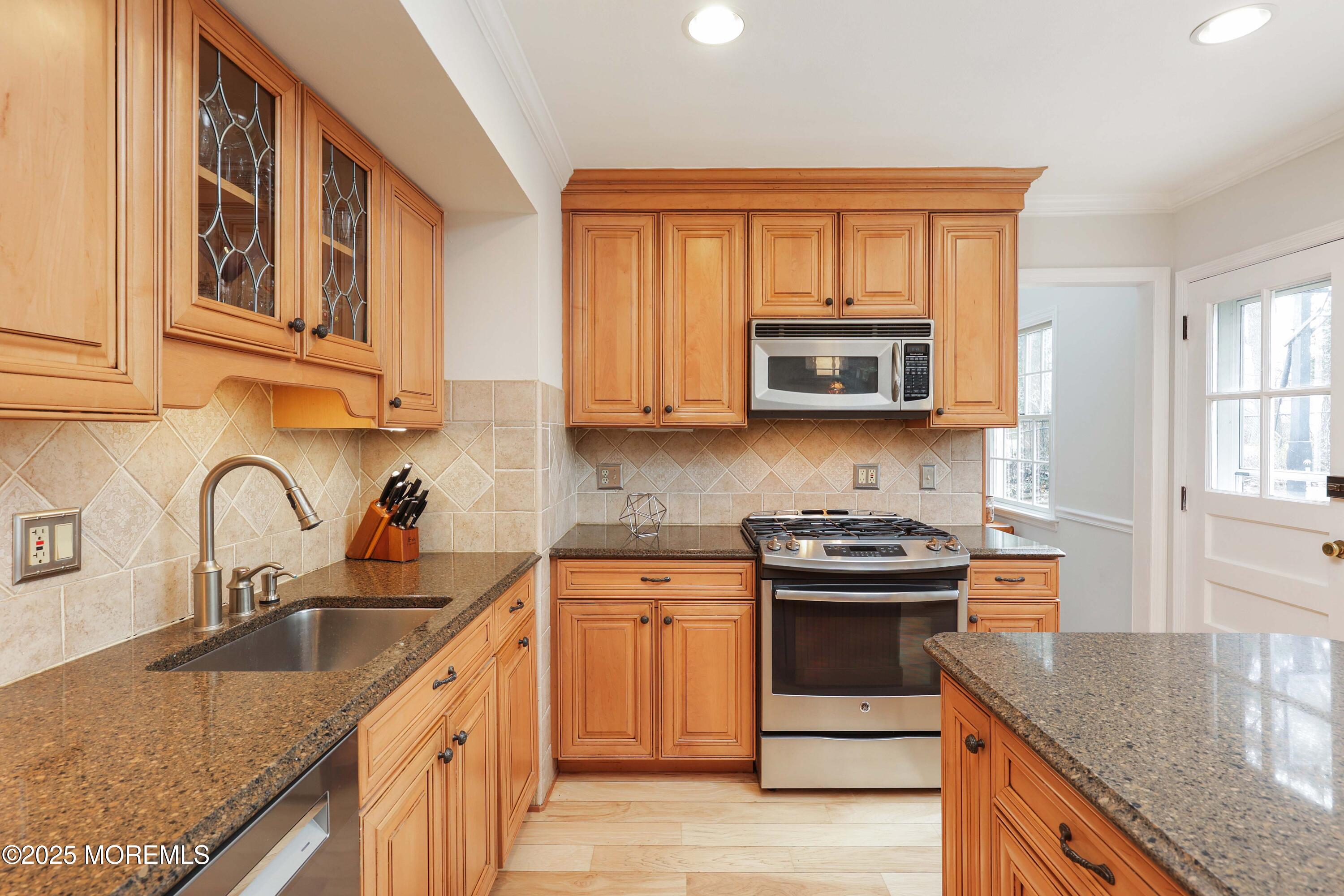 125 Jumping Brook Road Lincroft, NJ 07738 - Photo 32 of 47 a kitchen with stainless steel appliances granite countertop a sink stove and cabinets