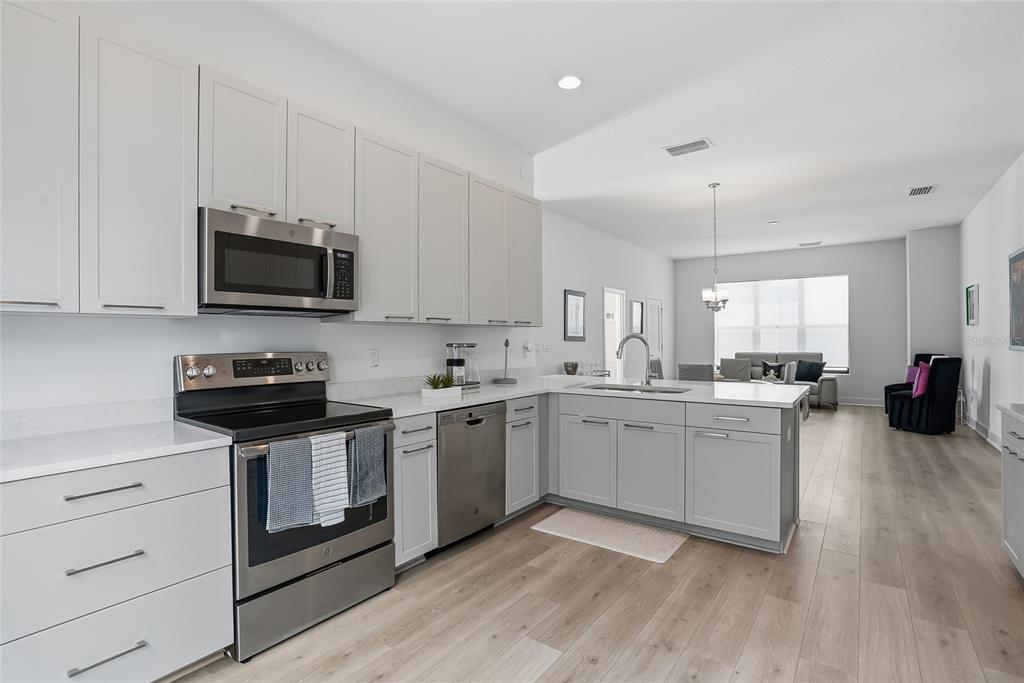 4810 West McElroy Avenue, Unit 30 Tampa, FL 33611 - Photo 4 of 43 a kitchen with stainless steel appliances granite countertop a stove top oven a sink dishwasher and a microwave oven with wooden floor
