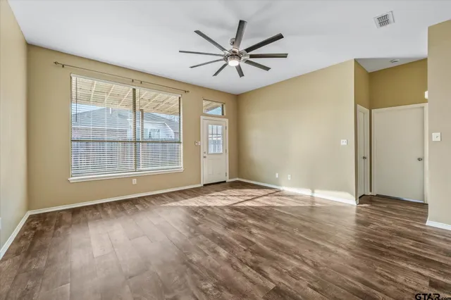 a view of an empty room with wooden floor and a window