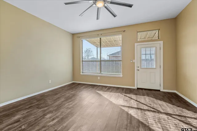 a view of an empty room with wooden floor and a window