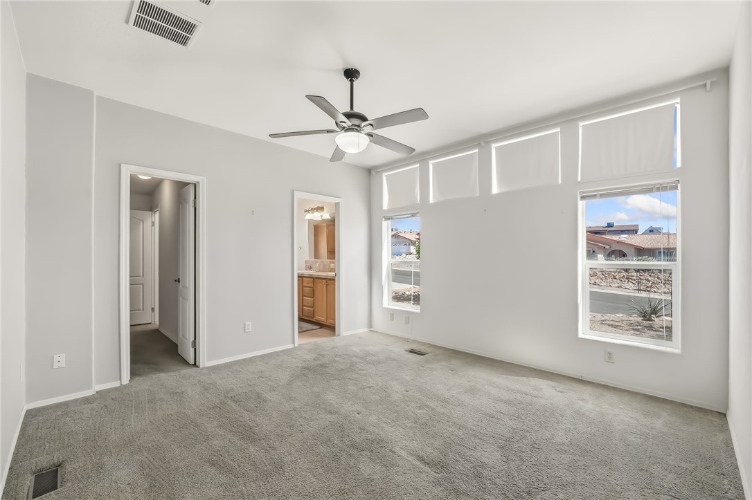 2525 South Ridge Avenue Bullhead City, AZ 86429 - Photo 39 of 76 Spacious room featuring light-colored carpeting, multiple windows with roller shades, and a ceiling fan with integrated lighting