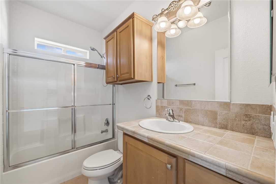 2525 South Ridge Avenue Bullhead City, AZ 86429 - Photo 53 of 76 En-Suite Bathroom featuring a tiled vanity with integrated sink, wood-finish cabinetry, and an overhead lighting fixture