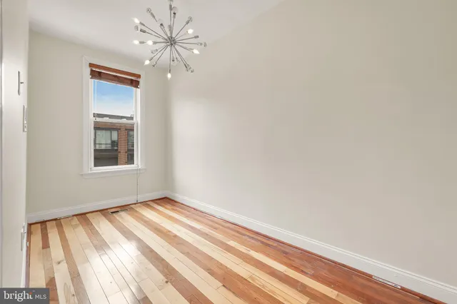 a view of an empty room with window and chandelier fan