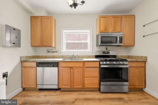a kitchen with granite countertop a stove a sink and a microwave