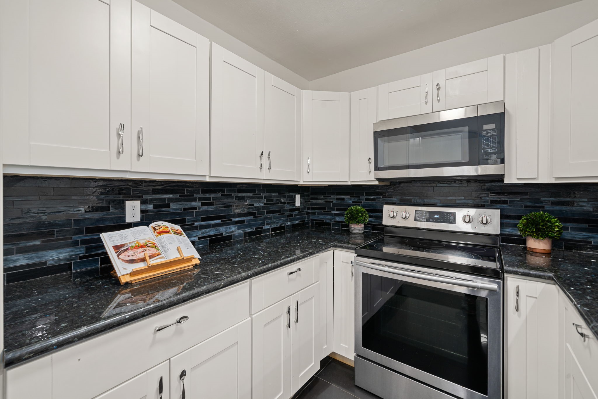 The sleek, modern kitchen is a young professional's dream, featuring granite countertops, stainless steel appliances, and striking, unique cabinet handles that ass a trendy, custom flair.
