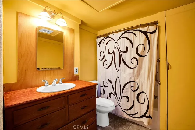 a bathroom with a granite countertop toilet a sink and a mirror